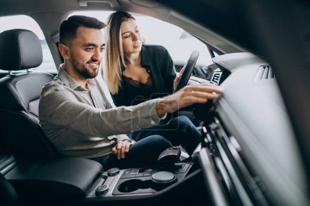 Téléchargez les photos : Jeune couple choisissant une voiture dans une salle d'exposition de voiture - en image libre de droit