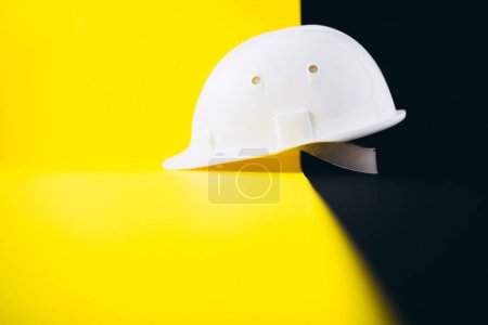 Photo for White hard hat isolated on a black and yellow background - Royalty Free Image