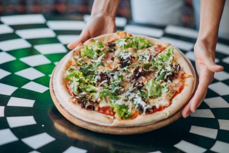Foto de La pizza sabrosa redonda se acercan a la mesa - Imagen libre de derechos