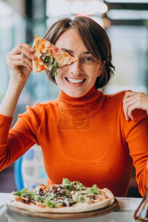 Photo for Young pretty woman eating pizza at pizza bar - Royalty Free Image