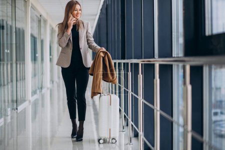 Téléchargez les photos : Femme d'affaires dans le terminal avec sac de voyage parlant au téléphone - en image libre de droit