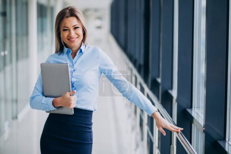 Photo for Young business woman with laptop standing in an office - Royalty Free Image