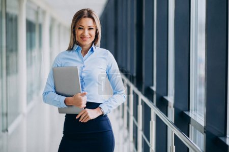 Photo for Young business woman with laptop standing in an office - Royalty Free Image
