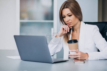 Téléchargez les photos : Belle femme d'affaires travaillant sur ordinateur au bureau et buvant du café - en image libre de droit