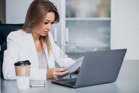 Téléchargez les photos : Belle femme d'affaires travaillant sur ordinateur au bureau et buvant du café - en image libre de droit