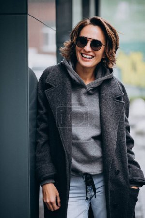 Téléchargez les photos : Jeune belle femme en manteau gris à l'extérieur de la rue - en image libre de droit