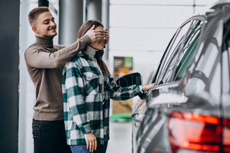 Photo for Young man presents a mcar to his girlfriend in a car showroom - Royalty Free Image