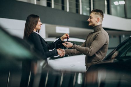 Photo for Young man with saleswoman at a car showroom - Royalty Free Image
