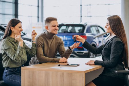 Photo for Young couple talking to a sales person in a car showroom - Royalty Free Image