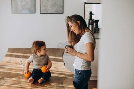 Téléchargez les photos : Jeune mère avec petit fils boire de l'eau à la maison - en image libre de droit