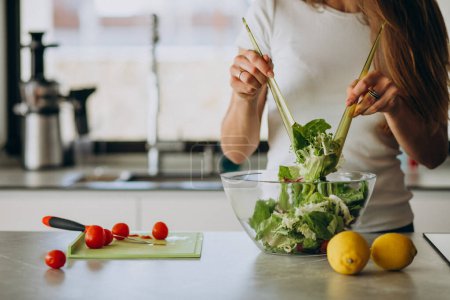 Photo for Young woman making salad at the kitchen - Royalty Free Image