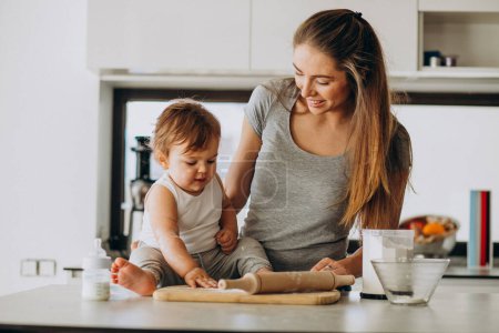 Téléchargez les photos : Jeune mère avec son petit fils cuisinant à la cuisine - en image libre de droit