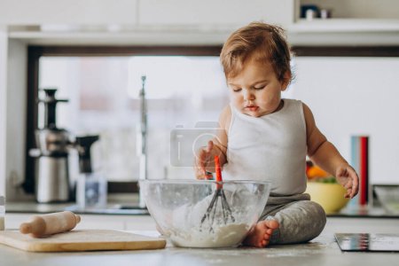 Téléchargez les photos : Mignon petit garçon cuisine à la cuisine - en image libre de droit