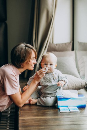 Téléchargez les photos : Mère avec son petit fils utilisant des serviettes pour le nez qui coule - en image libre de droit