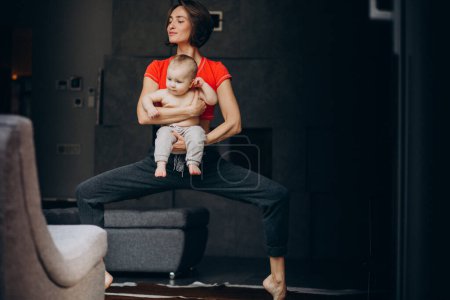 Téléchargez les photos : Jeune mère avec un petit fils pratiquant le yoga à la maison - en image libre de droit