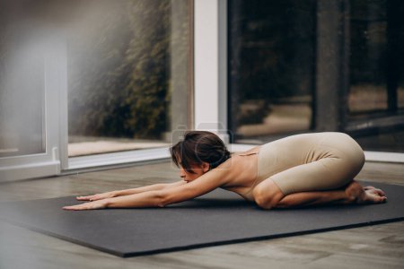 Téléchargez les photos : Jeune femme pratiquant le yoga à la maison - en image libre de droit