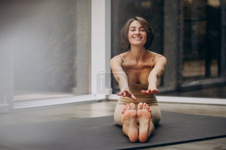 Téléchargez les photos : Jeune femme pratiquant le yoga à la maison - en image libre de droit