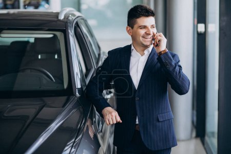 Photo for Young handsome business man in a car showroom choosing a car - Royalty Free Image