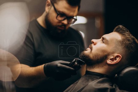 Foto de Hombre guapo cortando barba en un salón de peluquería - Imagen libre de derechos