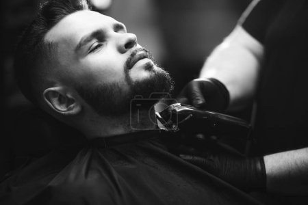 Foto de Hombre guapo cortando barba en un salón de peluquería - Imagen libre de derechos