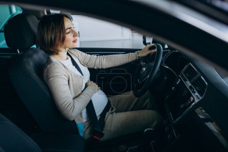 Photo for Young pregnant woman testing a car in car showroom - Royalty Free Image