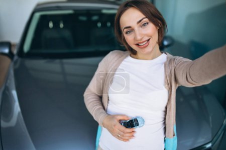 Foto de Mujer embarazada joven eligiendo un coche en una sala de exposición de coches - Imagen libre de derechos