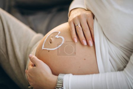 Photo for Pregnant woman applying cream on the belly to prevent stretches - Royalty Free Image