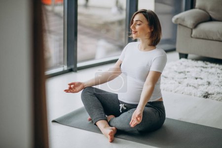 Téléchargez les photos : Jeune femme enceinte pratiquant le yoga à la maison - en image libre de droit