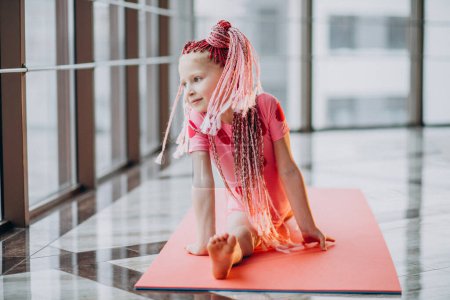 Téléchargez les photos : Petite fille mignonne faisant de la gymnastique sur tapis en studio - en image libre de droit