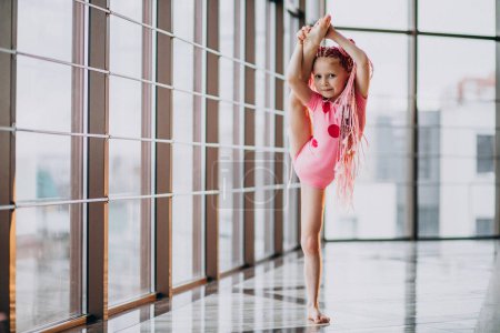 Téléchargez les photos : Petite fille mignonne faisant de la gymnastique sur tapis en studio - en image libre de droit