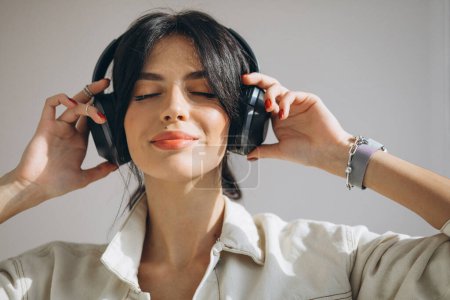 Photo for Young pretty woman listening music on wireless earphones - Royalty Free Image