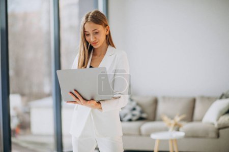 Téléchargez les photos : Jeune femme d'affaires en costume blanc travaillant sur un ordinateur - en image libre de droit