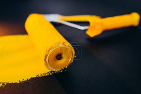 Photo for Paintroller for repairs isolated on black background in yellow paints - Royalty Free Image