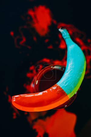 Téléchargez les photos : Banane teinte dans des peintures colorées sur fond noir - en image libre de droit