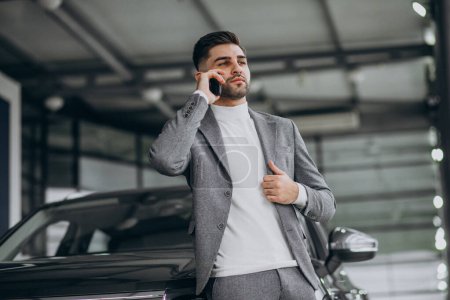Photo for Handsome business man talking on the phone in a car showroom - Royalty Free Image