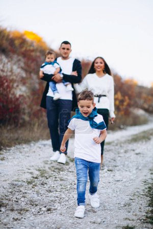 Téléchargez les photos : Jeune famille avec deux fils ensemble à l'extérieur du parc - en image libre de droit
