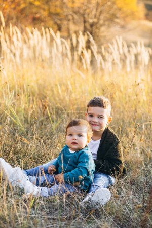 Photo for Two little baby brothers sitting together in field - Royalty Free Image