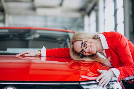 Photo for Elderly woman hugging an auto mobile at a car showroom - Royalty Free Image