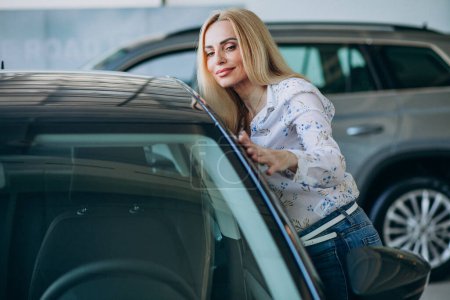 Téléchargez les photos : Femme d'affaires à la recherche d'un mobile automobile dans une salle d'exposition de voiture - en image libre de droit