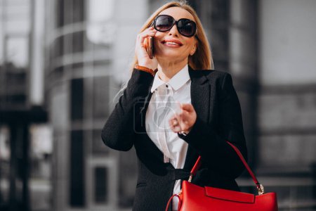 Photo for Business woman in classy outfit talking on the phone by the business center - Royalty Free Image
