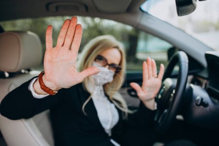 Photo for Business woman in protection mask sitting inside a car using antiseptic - Royalty Free Image