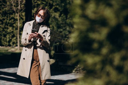 Téléchargez les photos : Femme d'affaires en manteau en utilisant le téléphone extérieur - en image libre de droit
