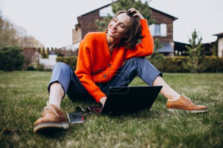 Téléchargez les photos : Jeune femme d'affaires avec ordinateur portable sur l'herbe - en image libre de droit
