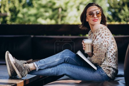 Photo for Young woman reading book and drinking coffee - Royalty Free Image