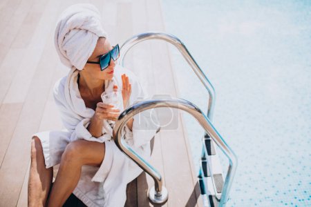 Téléchargez les photos : Jeune femme en peignoir buvant du café au bord de la piscine - en image libre de droit