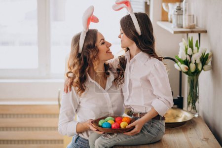 Téléchargez les photos : Mère avec sa fille peignant des œufs pour Pâques - en image libre de droit