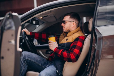 Foto de Retrato del hombre guapo sentado en el coche y tomando café - Imagen libre de derechos