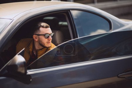 Téléchargez les photos : Portrait d'un bel homme assis dans une voiture - en image libre de droit