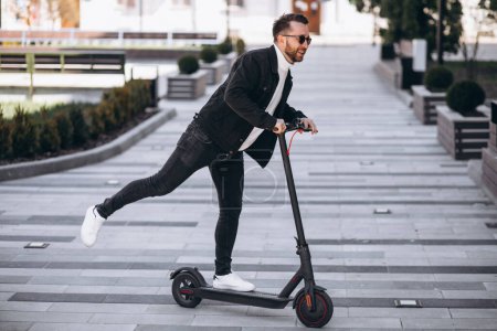 Téléchargez les photos : Jeune homme beau chevauchant sur scooter dans le parc - en image libre de droit