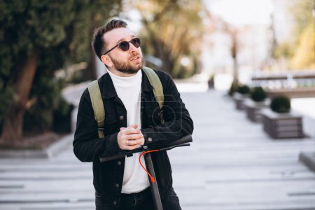Téléchargez les photos : Jeune homme beau chevauchant sur scooter dans le parc - en image libre de droit